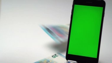 Kumarhane piyangosunda büyük ikramiye, cep telefonunun yanında dikey yeşil ekran krom anahtarı olan beyaz arka planda avroluk kağıt para birimini kazandı. Avro banknotları halinde nakit gelir, başarılı