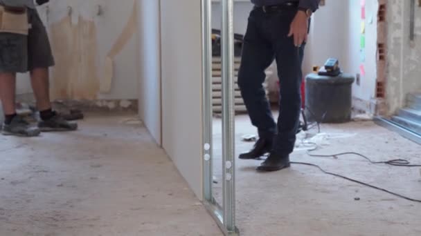 Trabalho em equipe no canteiro de obras em novo apartamento dentro de casa, trabalhadores profissionais modelagem placas de gesso e montagem drywalls com chave de fenda para perfis de metal. Reconstrução e engenharia de casas — Vídeo de Stock