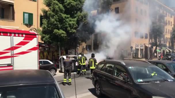 ROME, ITALY - JUNE 11, 2020: Rescue team of firefighters arriving on central road of Rome and extinguishing burning trash can with water hoses. Firemen preventing setting in fire of residential — Stock Video