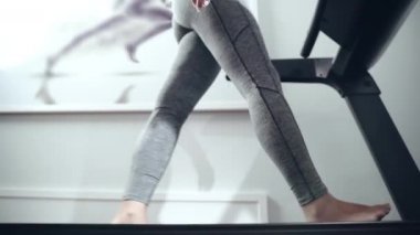 Spor giyimli, çıplak ayaklı bir kadının sağlık merkezinde yürüdüğü düşük açılı bir manzara. Düz taban sorunu olan genç bir sporcu, kadın hasta konsültasyon ve fizyoloji eğitimi alıyor.