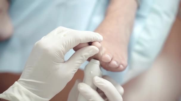 Close-up de ortopedistas mãos em luvas de proteção médica usando equipamento de pulsação lazer para examinar e curar pacientes problemas nos pés. Tecnologias modernas de lazer no centro médico, consulta — Vídeo de Stock