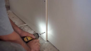 Profesyonel inşaat işçisi inşaat alanında elektrikli tornavidayla sıva tahtasında delikler açıyor. Foreman yeni dairede alçıtaşı kalıbını çıkarıyor. Endüstri kavramı, inşa ve