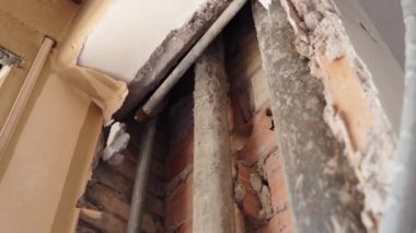 Terk edilmiş eski bir apartmanın inşaat sahasında tamirat çalışmaları, işçiler beton duvarı yıktılar ve içeride dikey hasarlı paslı borular buldular. Tuğla duvarın içindeki su boru hattı.