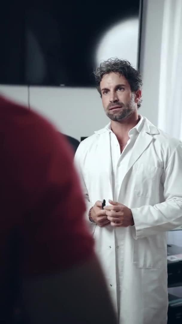 Vážná mužská lékařka v bílé uniformě má schůzku s pacientem v nemocničním pokoji, profesionální bělošský lékař drží pero v rukou a snaží se vysvětlit klidným pacientům lékařské — Stock video