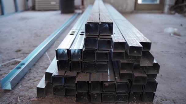 Building materials for remodeling walls on construction site. Stack of long metal profiles lying on the ground in new house, steel panels used for gypsum assembling and dividing apartment into many — Stock Video