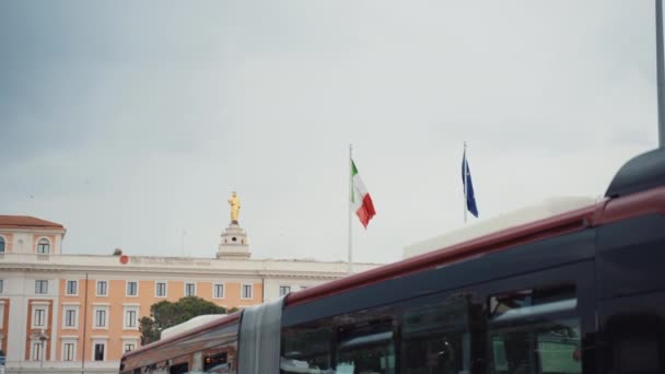 ROMA, ITALIA - 3 DE JULIO DE 2020: Banderas de la unión italiana y europea en el fondo del increíble edificio histórico en la estación central de Roma Termini, vista de la estación de autobuses en el clima nublado, transporte público en — Vídeo de stock