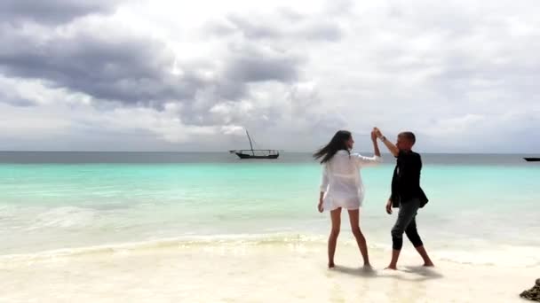 ちょうど夫婦が海の真ん中に素晴らしい海賊船を背景に海のビーチで踊ります。幸せな恋人繰り返しそれ最初結婚式ダンスの新婚旅行で熱帯エキゾチックな場所 — ストック動画