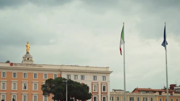 ローマ、イタリア- 2020年7月3日:ローマのテルミニ駅の古代の歴史的建造物を背景に吹いている記号や記号、イタリアとヨーロッパの組合旗の概念 — ストック動画