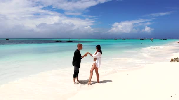 Νεαρό ζευγάρι χορεύει στην παραλία στις καλοκαιρινές διακοπές, κύριος φιλάει το χέρι της όμορφης κυρίας του με μπικίνι. Χαρούμενη σχέση μεταξύ άνδρα και γυναίκας, χαλάρωση και μήνας του μέλιτος απολαμβάνοντας — Αρχείο Βίντεο