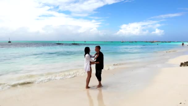 Casal romântico amantes dançando na praia do mar com areia branca e água azul-turquesa. Jovens mostrando seu amor e carinho, abraçando, olhando uns para os outros e dançando. Romance e — Vídeo de Stock