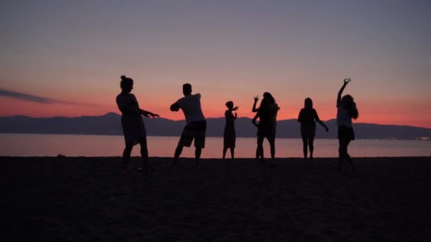 Vacker havssolnedgång bakgrund, skara glada glada glada vänner dansar barfota vid havet stranden. Silhuetter av dansande människor lyfter upp sina händer. Beach party bakgrund — Stockvideo