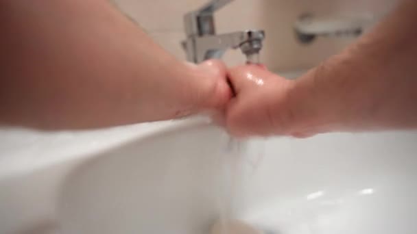 Close-up van mannelijke handen spoelen van zeepschuim onder warm water in badkamerkraan, zorgvuldig wassen van de handen na contact met andere mensen buiten of thuis. Hygiënevoorschriften ter voorkoming van — Stockvideo