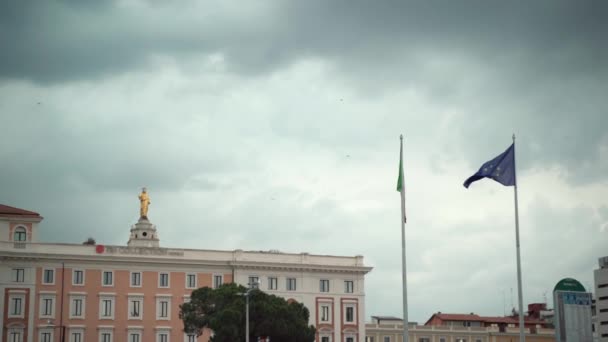 ŘÍM, ITÁLIE - 3. června 2020: Evropská unie a italské vlajky visí na nádraží Roma Termini na pozadí starobylých historických budov, slavného autobusového, vlakového a letištního nádraží plného cestujících — Stock video