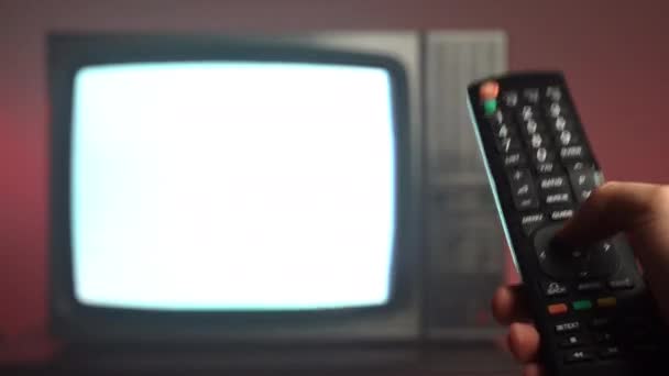 Erkeklerin el ele tutuştuğu klasik TV uzaktan kumandası ve televizyon kanalı değiştirmek için düğmelere basıldığı yakın plan — Stok video