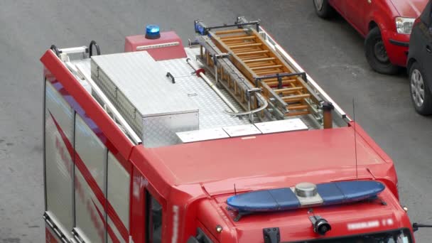 Pohled shora na blikající modrou sirénu hasičského vozu, červený hasičský vůz přijíždějící na místo požárního poplachu, záchranná hasičská služba s různým vybavením pro záchranné operace. Nouzové znamení a hasiči