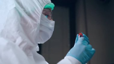Laboratuvarda, kovid 19 enfeksiyon kapmış hastaların kan test tüpleriyle çalışan koruyucu kadın tıp uzmanı bilim adamı kan plazması üzerinde laboratuvar araştırmaları yapıyor. Tıbbi