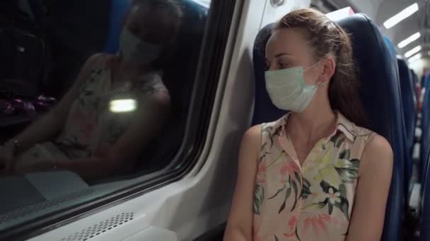 Mujer triste en máscara médica conduciendo en tren y mirando por la ventana mientras pasa túnel oscuro. Concepto de uso de mascarilla protectora en el transporte público como medidas de precaución durante — Vídeos de Stock