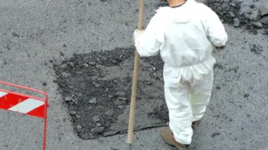 Beyaz kaplama üniformalı işçiler demir kürek kullanarak kaldırım yolunun yıkılmış kısmına çimento solüsyonu yerleştiriyor. İnşaat alanına çimento dökme süreci, mühendislik konsepti