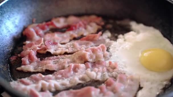 Evde İngiliz kahvaltısı hazırlama süreci, tavada yumurtalı domuz pastırması kızartma. Pişirme yağlı kızartma, lezzetli sağlıksız yeme konsepti. — Stok video