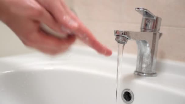 Personen tvättar händerna i badrummet, löddrar med antibakteriell tvål, gnuggar fingrar och tassar, sköljer under varmt vatten i kranen. Stränga regler för att förhindra spridning av virusinfektion — Stockvideo