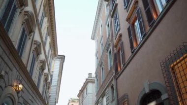 Gökyüzü arka planında güzel bir bina, geniş pencereli ve renkli panjurlu uzun antik binalar, şehir caddesini ve apartman cephesini aydınlatan lambalar. İtalyan mimarisi