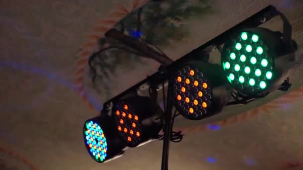 Färgglada blinkande spotlights hängande i taket och lysande utrymme, fyra neonljus blinkar på disco fest, bröllop eller födelsedagsfest, eller på nattklubb underhållning. Ljusutrustning — Stockvideo