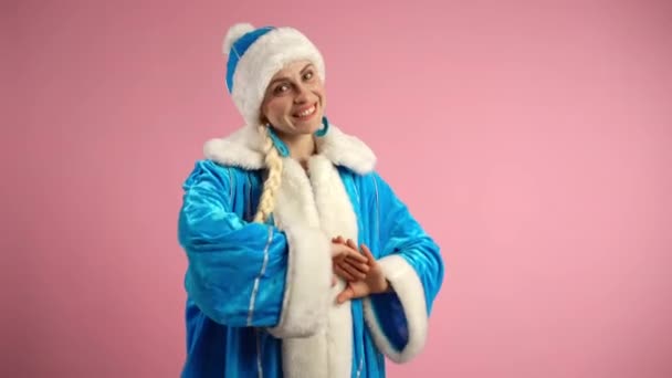 Pamuk Kız 'ın mavi kostümlü, beyaz kürklü, uzun örgülü mavi şapkalı güzel bir kadın pembe arka planda dans eden mutlu bir Noel Baba kadın. — Stok video
