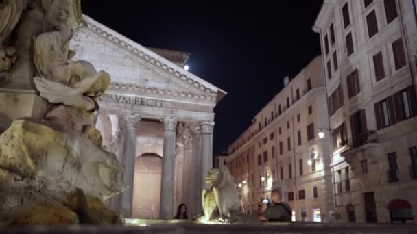 令人惊奇的是，罗马的万神殿在夜间被照亮，大理石古泉在教堂背景上流淌着水。万神殿是罗马的一个历史遗迹 — 图库视频影像