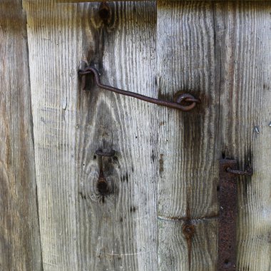 Gri ahşap arka planda dövülmüş eski bir demir kale..