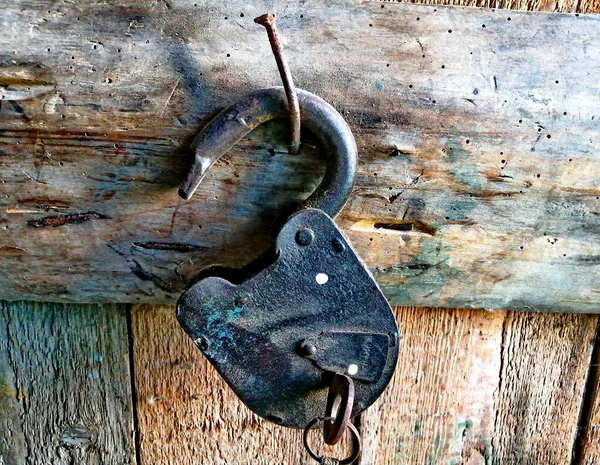 An old barn lock with keys, in a wooden shed, hanging from a large nail. Close-up photo.