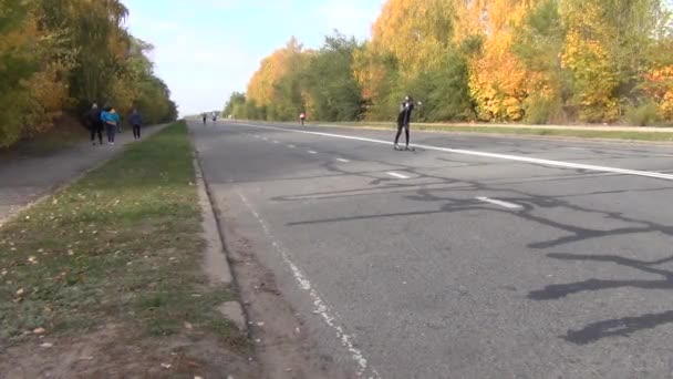 Tolyatti Samaran alue Venäjä-lokakuu 04 2020: Kaupunkipuisto. Vanhempi mies ratsastaa rullaluistimilla. — kuvapankkivideo