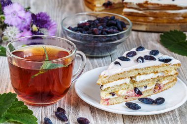 Hanımeli ve ahşap bir tabloda çay ile pasta.