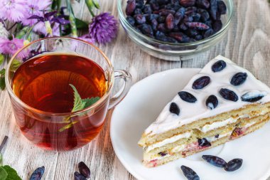 Hanımeli ve ahşap bir tabloda çay ile pasta.