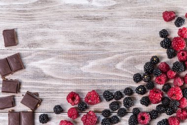 Böğürtlen, ahududu ve ahşap arka plan üzerinde kırık çikolata.