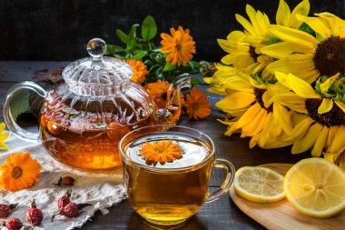 Kadife çiçeği ve koyu ahşap arka plan üzerinde köpek rose ile çay.