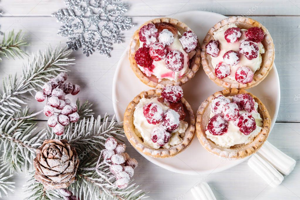 Tartlets with cottage cheese and raspberries on a bright table.