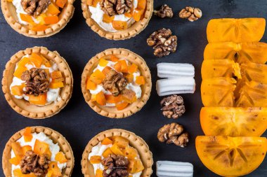 Tartlets lor krem ve karanlık bir arka plan üzerinde Trabzon hurması.