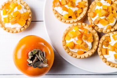 Tartlets lor krem ve hafif bir arka plan üzerinde Trabzon hurması.