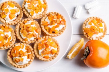 Tartlets lor krem ve hafif bir arka plan üzerinde Trabzon hurması.