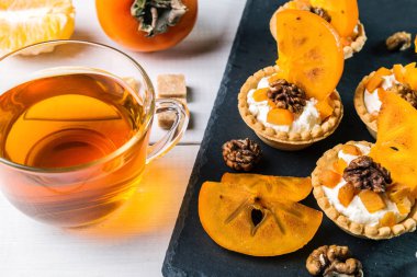 Lor krem, Trabzon hurması ve şeffaf bir fincan çay ile Tartlets.