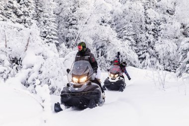 Güney Urallar 'ın dağlarındaki kış ormanlarında hareket eden kar motosikletli sporcular.