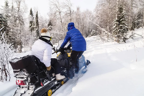 Athletes on a snowmobile moving in the winter forest in the mountains of the Southern Urals.