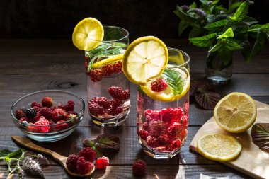 Ahududu, limon ve nane karanlık bir arka plan üzerinde serinletici içecek.