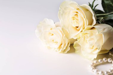 Beyaz gül ve beyaz zemin üzerine inci kolye.