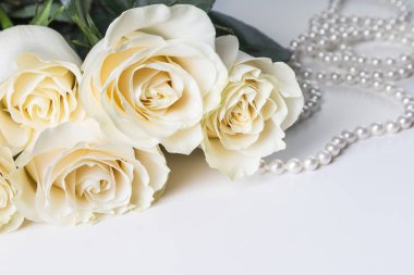 Beyaz gül ve beyaz zemin üzerine inci kolye.