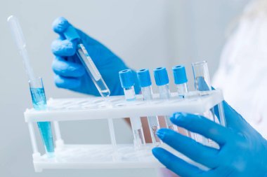 Laboratuvar önlüklü ve reaksiyonlu bir bilim adamı ya da doktor. İçinde kimyasal sıvı bulunan laboratuvar camları..