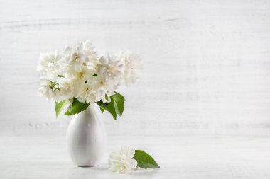 Yasemin çiçekleri ahşap bir arka planda vazoda.