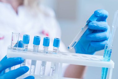 Laboratuvar önlüklü ve reaksiyonlu bir bilim adamı ya da doktor. İçinde kimyasal sıvı bulunan laboratuvar camları..