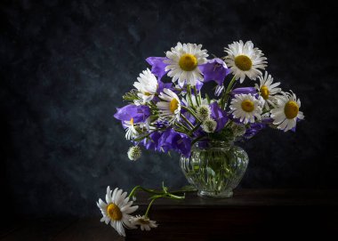 Koyu arkaplanda bir buket papatya ve çan..