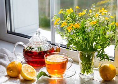 Limonlu ve naneli çay ve güneşli bir günde pencere eşiğinde bir buket çiçek..